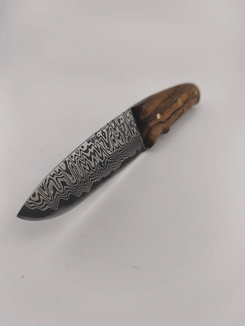Couteau artisanal : les motifs contrastés du damas couvrent les flancs de la lame.