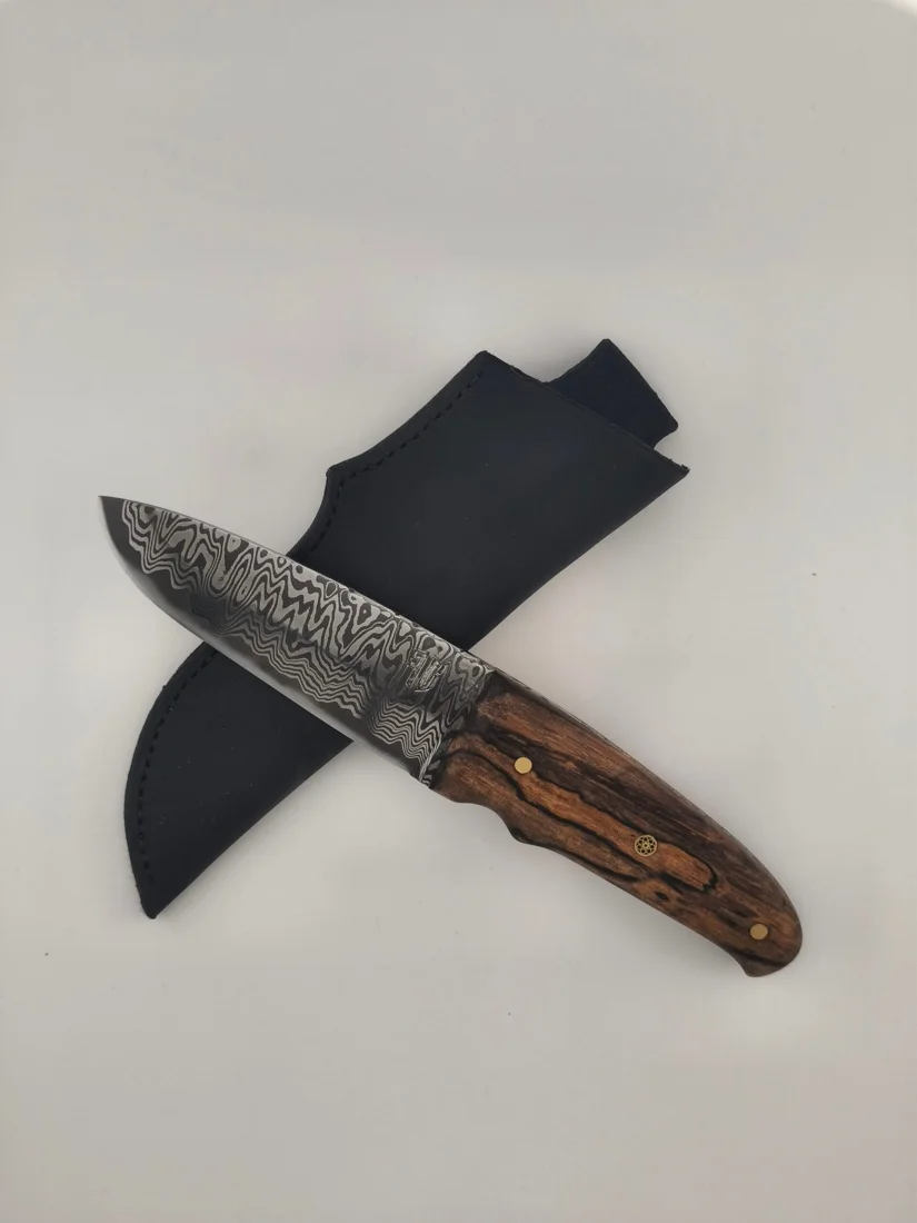 Couteau en damas et son étui en cuir noir, disposés sur un fond clair.